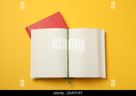 Opened empty book and red book on yellow background, space for text Stock Photo