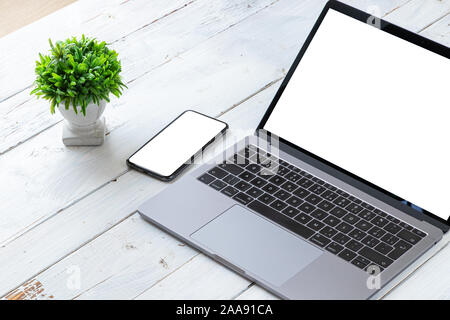 The Laptop and phone with blank screens on white wooden table. Workspace. Copy space. Stock Photo