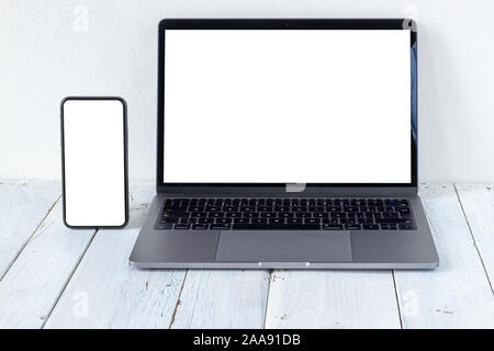 The Laptop and phone with blank screens on white wooden table. Workspace. Copy space. Stock Photo