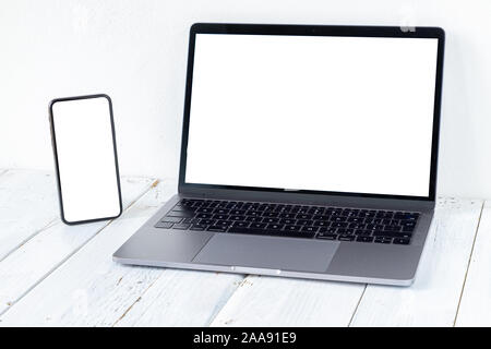 The Laptop and phone with blank screens on white wooden table. Workspace. Copy space. Stock Photo