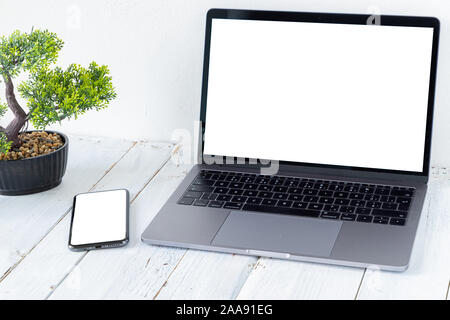 The Laptop and phone with blank screens on white wooden table. Workspace. Copy space. Stock Photo