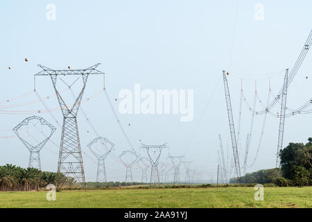 View of high electric voltage transmission tower, power pylon poles and electrical distribution substation on Amazon rainforest, Amazonas, Brazil. Stock Photo