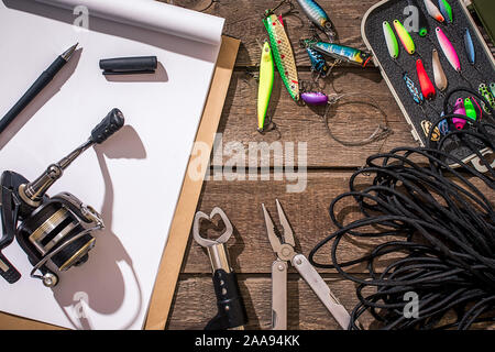 Fishing tackle. Fishing rod, fishing hooks, landing net and pliers on old  wooden background with free space for text Stock Photo - Alamy