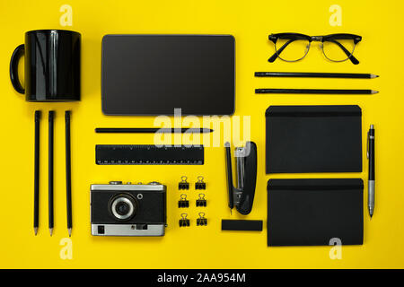 Black objects from the office on a yellow background. Work and creativity. Social media concept hero header image. Top view. Still life. Copy space Stock Photo