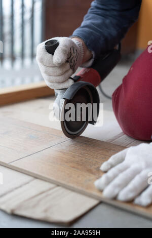 repair and decoration. a man cuts ceramic tiles with a grinder. Stock Photo