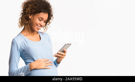 African-american pregnant woman messaging on cellphone, free space Stock Photo