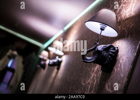 Dancing elephants lamp at luminous lamp, in the form of an elephant, illuminates a wall, a floor lamp. unusual angle Stock Photo