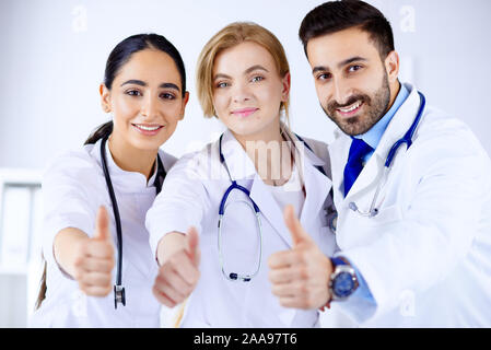 Three young doctors shows thumb up Stock Photo