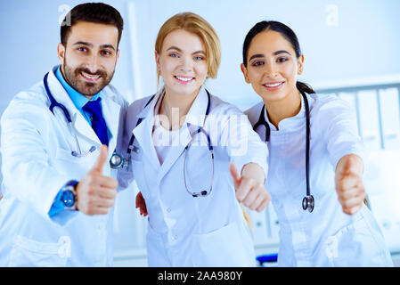 Three young doctors shows thumb up Stock Photo