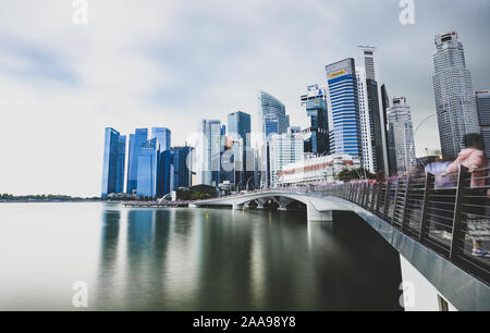 Stunning view of the financial district of Singapore during a cloudy day with the Merlion Statue in the distance.
