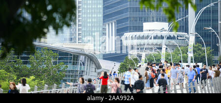 (Focus on the background) Defocused crowd of local people and tourists walking on a bridge in Singapore. Stock Photo
