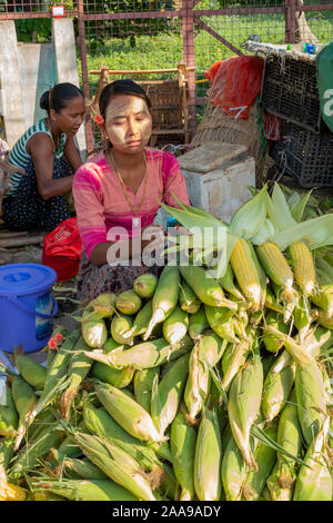 The lively meat,fish,vegetable & fruit market of Pakokku, Myanmar (Burma) with a young woman selling fresh corn. Stock Photo