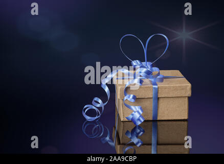 One small cardboard box with blue ribbons on dark background Stock Photo