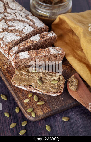 Fresh home baked rye bread with homemade pumpkin seed spread on wooden board Stock Photo