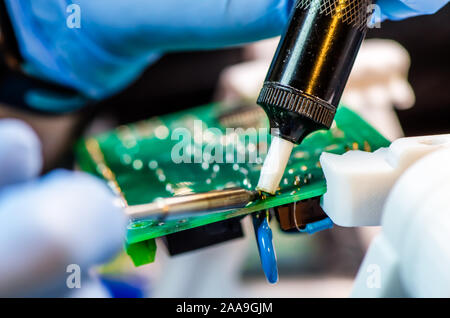 Technical support worker drops the fee PCB. Soldering iron. Tweezers Stock Photo