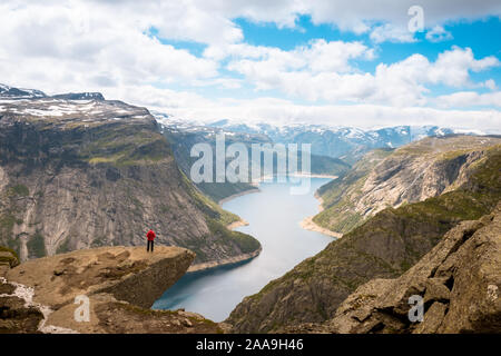 Sporty woman posing on Trolltunga. Happy hiker enjoy beautiful lake and good weather in Norway. Stock Photo
