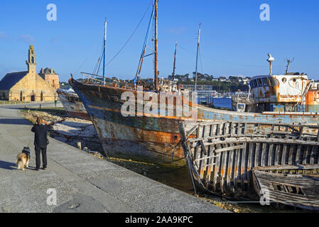 Tourist visiting wrecks of old wooden trawler fishing boats / lobster boats in the harbour / port of Camaret-sur-Mer, Finistère, Brittany, France Stock Photo