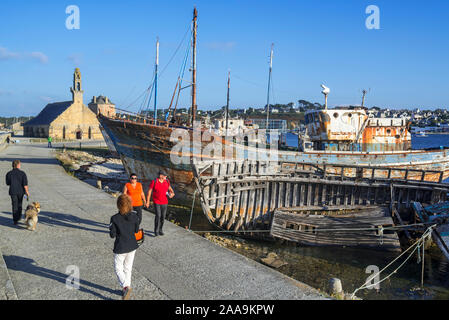 Tourists visiting wrecks of old wooden trawler fishing boats / lobster boats in the harbour / port of Camaret-sur-Mer, Finistère, Brittany, France Stock Photo