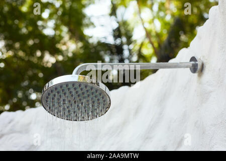 Outdoor rain shower head under palm trees and sunny beautiful blue sky. Living and nature harmony, spa resort hotel lifestyle. Relaxing leisure Stock Photo