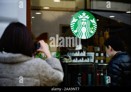 Prague, Czech Republic. 18th Nov, 2019. Tourists stand in front of a Starbucks coffee.Prague the capital city of the Czech Republic and one of the top European Tourist destinations is known for the Old Town Square with baroque buildings, Gothic churches and the world known medieval Astronomical Clock and the pedestrian Charles Bridge decorated with statues of Catholic saints. Credit: Omar Marques/SOPA Images/ZUMA Wire/Alamy Live News Stock Photo