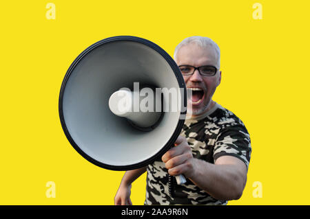 Closeup portrait of a young man screaming into a megaphone. isolate on a yellow background Stock Photo