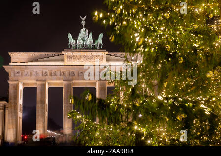 Illuminated Neoclassical Brandenburg Gate (Brandenburger Tor) and Christmas Tree as viewed from the Pariser Platz, Mitte, Berlin, Germany Stock Photo