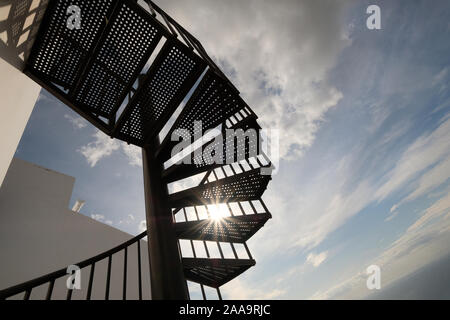 Spiral staircase from below against sun and cloud-sky Stock Photo