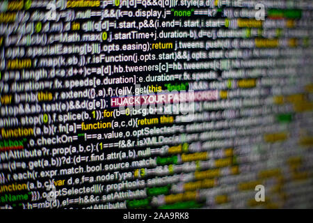 Macro photo of computer screen with program source code and highlighted HIJACK YOUR PASSWORDS inscription in the middle. Script on the screen with Stock Photo