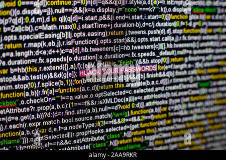 Macro photo of computer screen with program source code and highlighted HIJACK YOUR PASSWORDS inscription in the middle. Script on the screen with Stock Photo