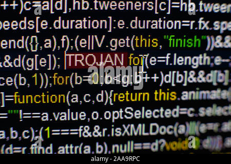 Macro photo of computer screen with program source code and highlighted TROJAN inscription in the middle. Script on the screen with virus in it. Cyber Stock Photo