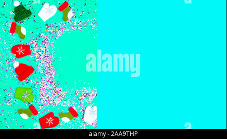 Colorful Sparkling holographic glitter confetti, toy hats, mittens, boots. Christmas Holidays abstract blue background Stock Photo
