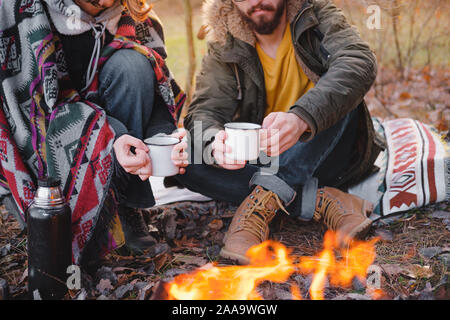 Two people having a lovely time outdoors with a pet in autumn. Man and woman in warm clothes sit outdoors together with their dog on a lovely chilly d Stock Photo