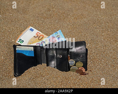 open black wallet with euro banknotes and coins in the sand on beach Stock Photo