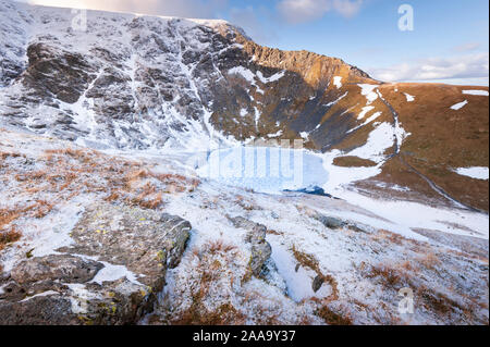 English Lake District mountain landscape Sharp Edge in ice and  winter snow above frozen Scales Tarn on Blencathra a North East Lakeland Fell Stock Photo