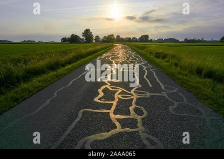 Light of setting sun reflecting on structure of repairs on tarmac road. Stock Photo