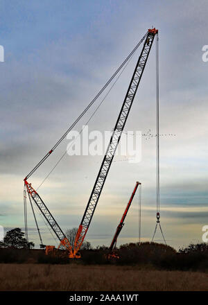 Early morning geese fly past a giant crane that will be used to replace a railway bridge over the canal near Burscough. Stock Photo