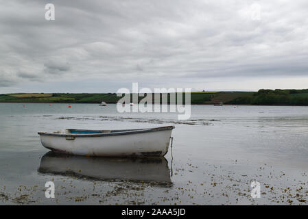 White rowing boat moored with reflections in water with boats and land out of focus in the background. Fishing concept Stock Photo