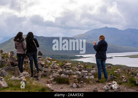 Tourists taking pictures to Rock balancing or stone balancing in Loch Loyne, Northwest Highlands of Scotland, UK Stock Photo