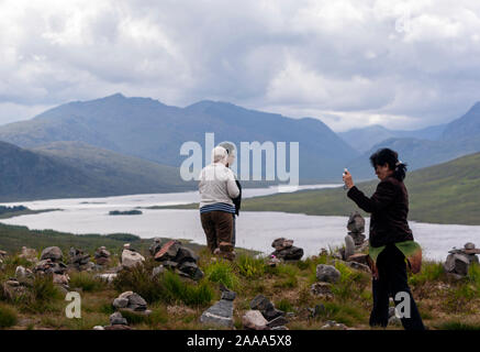 Tourists taking pictures to Rock balancing or stone balancing in Loch Loyne, Northwest Highlands of Scotland, UK Stock Photo
