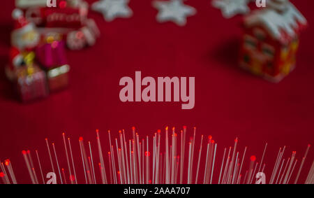 Fiber optic light cables with blurred Christmas ornaments on red background, photo-illustration Stock Photo