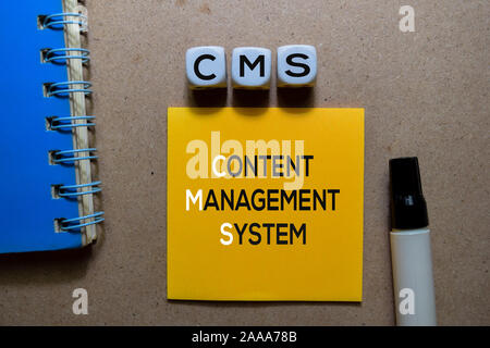 CMS - Content Management System write on Sticky note. Isolated on wooden table Stock Photo
