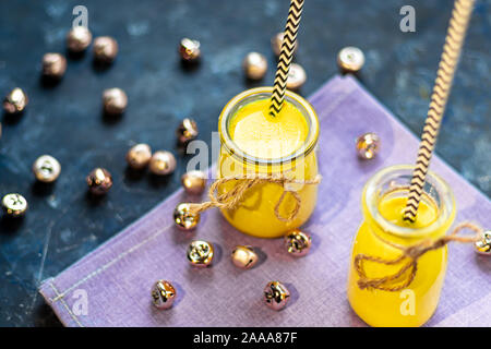 Golden milk with spices. Turmeric, cloves, black pepper and a drop of vegetable oil. Traditional indian drink. On a dark background. Healthy eating Co Stock Photo