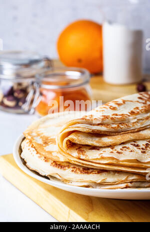Thin pancakes on white rustic table, ingredients, making blini, domestic kitchen and crepes Stock Photo