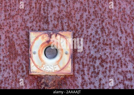 An old stop and reset button mounted on a rusted metal plate Stock Photo