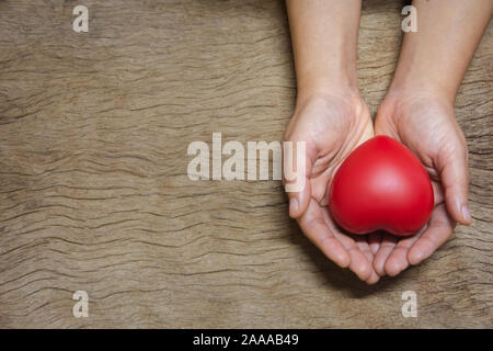 Hands holding red heart on wood plank background with copy space Stock Photo