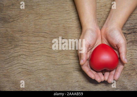 Hands holding red heart on wood plank background with copy space Stock Photo