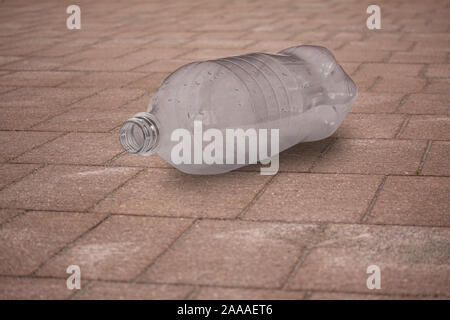 Empty plastic bottle lying on wooden boardwalk tossed away. Close up image with selective focus. Environment concept. Close up image. Stock Photo