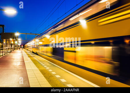 Blurred moving dutch train leaving the Amersfoort Vathorst station with an empty platform. Stock Photo