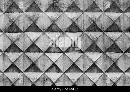 Part of a light concrete fence with rhombuses. White relief concrete wall with geometric shapes. Stock Photo