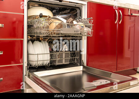 freshly washed clean dishes in the dishwasher, red kitchen cabinets.